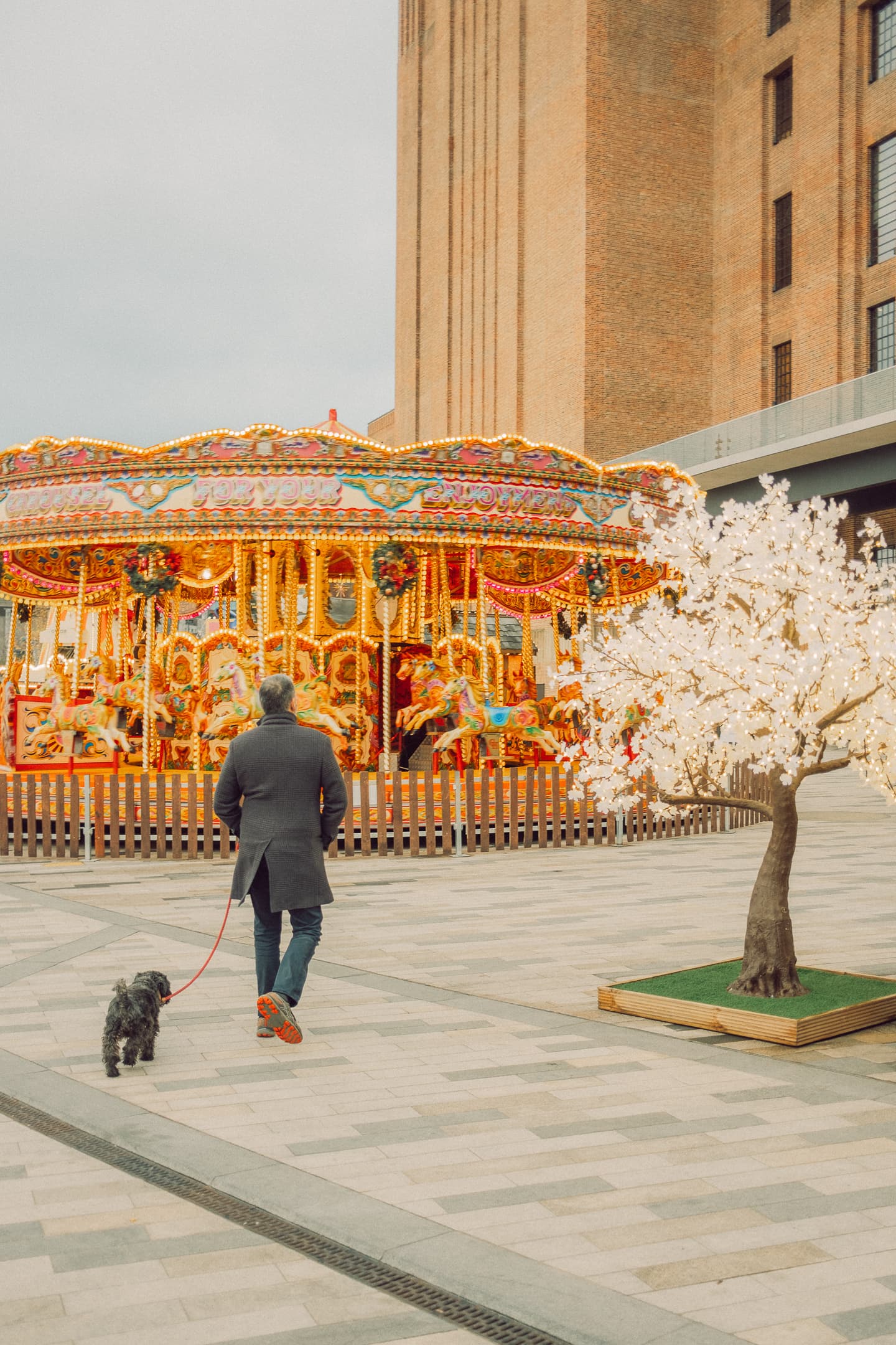 Homme promenant son chien devant le carrousel de Battersea Power Station